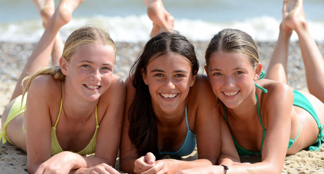 Séjours linguistiques à Exmouth avec LISA! – plage, soleil et expériences inoubliables pour étudiants Étudiantes sur la plage à Exmouth lors d’un séjour linguistique LISA! allongées sur le sable profitent du soleil et de la mer