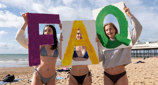 FAQ sur les séjours linguistiques en Angleterre Bournemouth avec LISA! – questions et réponses Trois participantes sur la plage de Bournemouth tiennent des panneaux FAQ lors d’un séjour linguistique LISA! en Angleterre