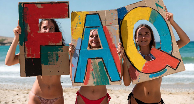 FAQ séjours linguistiques LISA! – réponses aux questions fréquentes Trois jeunes femmes sur la plage tiennent des panneaux FAQ lors d’un séjour linguistique LISA!