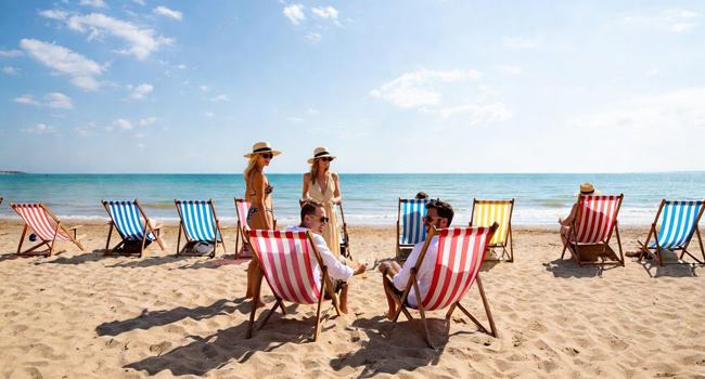 Séjours linguistiques pour adultes en Angleterre Bournemouth avec LISA! – plage, soleil et détente Participants adultes se détendant sur des transats à la plage de Bournemouth lors d’un séjour linguistique LISA! en Angleterre