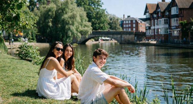 Adultes participants à un séjour linguistique LISA! à Cambridge City Angleterre assis au bord de la rivière profitent du soleil et du temps libre