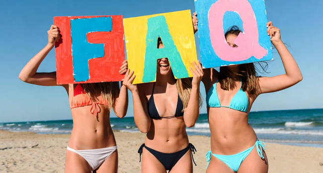 Participantes adultes féminines à un séjour linguistique à Malte sur la plage avec des panneaux de questions fréquentes et réponses