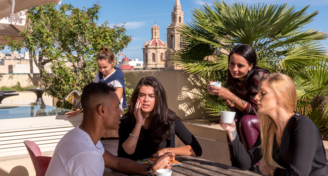 Participants à un séjour linguistique pour adultes à Malte sur la terrasse sur le toit de l’école de langues à Sliema avec vue sur la ville