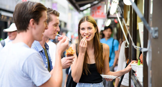 Congé de formation Osaka Japon avec LISA! – apprendre le japonais, street food et expériences authentiques Adultes goûtent de la street food à Osaka lors d’un congé de formation LISA! découvrent la cuisine japonaise et la vie urbaine internationale