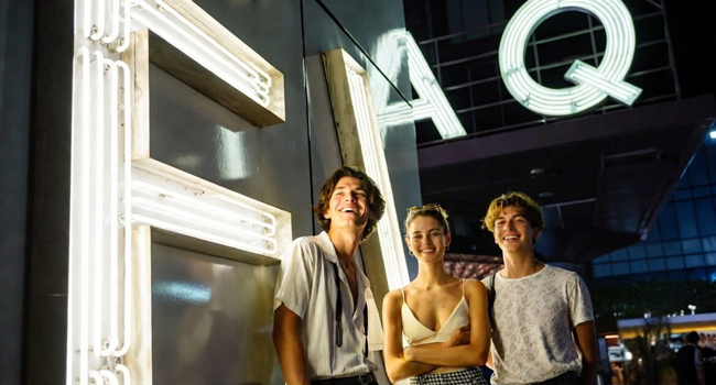Séjours linguistiques Tokyo Chiyoda avec LISA! – vie nocturne, ville et expériences inoubliables Jeunes adultes devant une enseigne lumineuse FAQ à Tokyo lors d’un séjour linguistique LISA! profitent de la vie nocturne