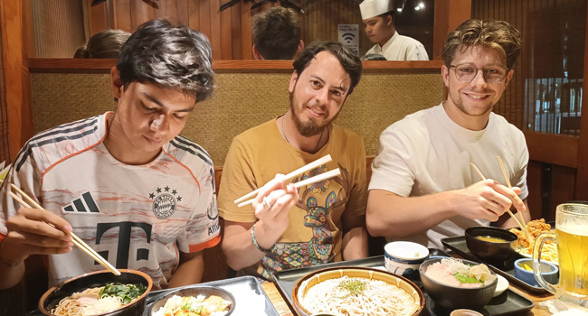 Séjours linguistiques Tokyo Chiyoda avec LISA! – loisirs, gastronomie et expériences culturelles au Japon Adultes dégustent de la cuisine japonaise à Tokyo lors d’un séjour linguistique LISA! découvrent la culture avec des baguettes