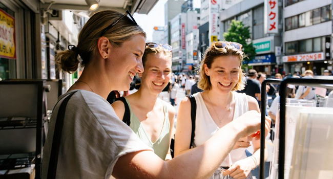 Séjours linguistiques Tokyo Chiyoda avec LISA! – street food, shopping et expériences authentiques au Japon Adultes achètent de la street food à Tokyo lors d’un séjour linguistique LISA! découvrent des spécialités locales et la culture