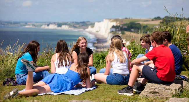 Groupe d’étudiants à Eastbourne Angleterre lors d’un séjour linguistique LISA! assis sur les falaises avec vue sur la mer