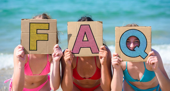 Trois étudiantes sur la plage à Bournemouth Park Angleterre tiennent des panneaux FAQ lors d’un séjour linguistique LISA!