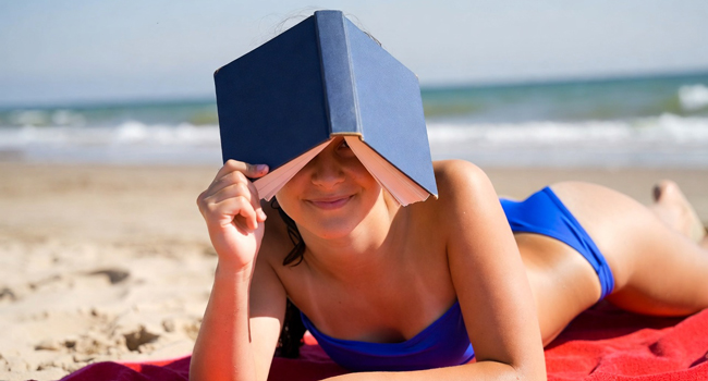 Étudiante lisant un livre sur la plage à Bournemouth Park Angleterre lors d’un séjour linguistique LISA! se détend au bord de la mer