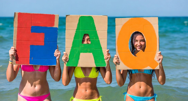 FAQ séjours linguistiques LISA! Exmouth – réponses pour étudiants Étudiantes sur la plage à Exmouth tiennent des lettres FAQ lors d’un séjour linguistique LISA! avec la mer en arrière-plan