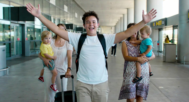 Étudiant arrivant à l’aéroport avec les bras levés enthousiaste pour un séjour linguistique LISA! pour étudiants