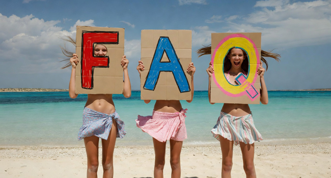 Trois étudiantes d’un séjour linguistique pour étudiants à Malte à Salina Beach avec de grandes lettres FAQ devant la mer