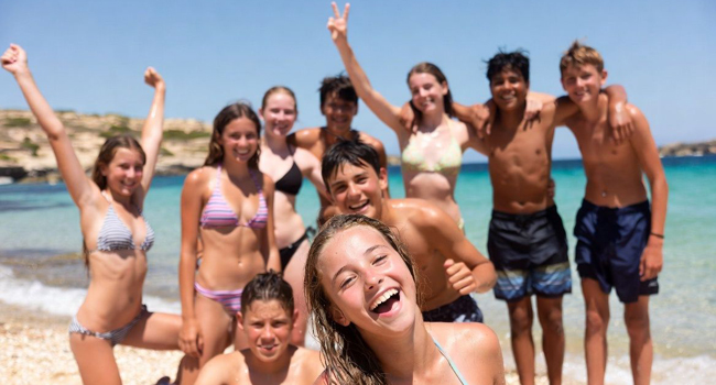Dix adolescents sur la plage à Malte San Gwann pendant le programme d’activités avec les bras levés