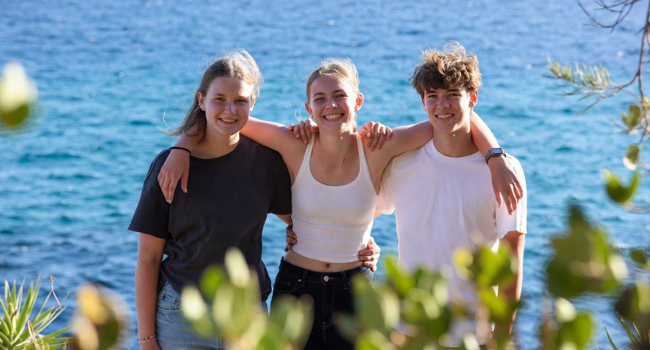Trois étudiants au bord de la mer s’embrassant en signe d’amitié lors d’un séjour linguistique à Malte San Gwann