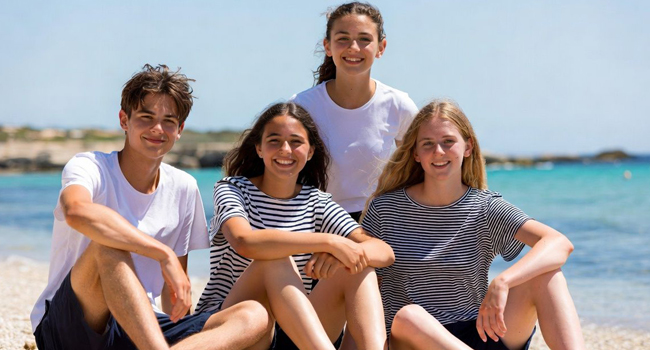 Quatre étudiants assis sur la plage à Malte lors d’un séjour linguistique LISA! pour étudiants