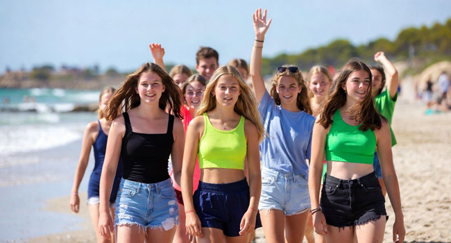 Jeunes adultes marchant sur la plage à Majorque lors d’un séjour linguistique LISA! profitent de la mer et du temps ensemble