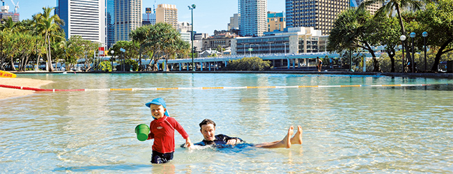 Kinder spielen im flachen Wasser mit Stadtblick im Hintergrund in Brisbane während einer LISA! Sprachreise