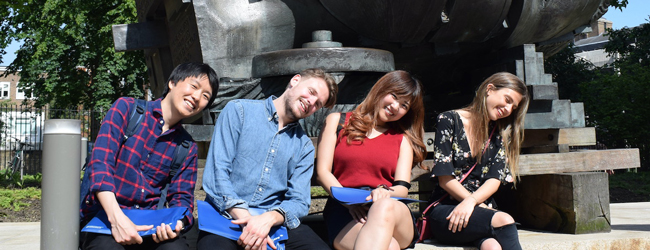 Posieren für die Kamera bei einem LISA! Sprachkurs Englisch in London Zwei Männer und zwei Frauen posieren mit geneigten Köpfen vor einem Kunstwerk in London