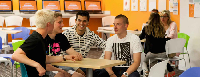 Vier junge Männer unterhalten sich in der Pause an der Sprachschule in Los Angeles