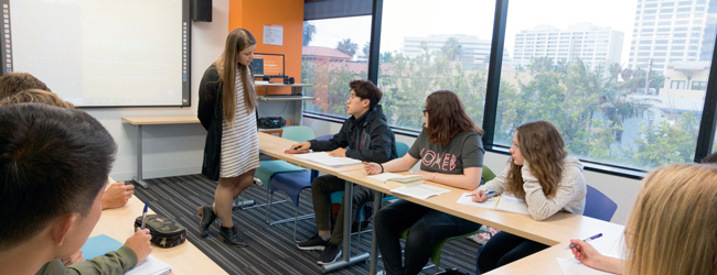 Lehrerin hört auf einen Schüler im Klassenraum mit Ausblick auf Los Angeles