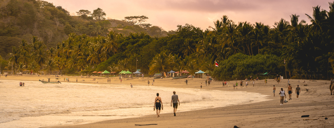 Strandspaziergang in Sámara in Costa Rica am Abend bei einer Sprachreise Bucht in Sámara mit Wellen, Spaziergängern und Palmen am Abend