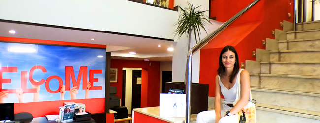 Willkommen in der Spanisch-Sprachschule auf Mallorca Eine Frau sitzt lächelnd auf der Treppe in der Lobby der LISA! Sprachschule in Palma de Mallorca