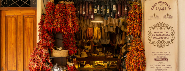 Feine Köstlichkeiten in einem Geschäft in Palma de Mallorca Offenes Geschäft mit Wurstwaren und roten Pimentos, die von der Decke hängen auf Mallorca
