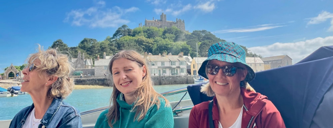 Drei damen fahren Boot im Hintergrund ein Schloss in Cornwall