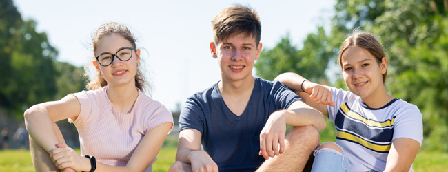 Drei Jugendliche sitzen auf einer Wiese im Sonnenschein bei einer Sprachreise für Schüler in Bath