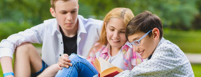 Lesen und chillen bei einer Schülersprachreise in England in Bedford Drei Jugendliche sitzen zusammen auf einer Wiese bei einer LISA! Sprachreise für Schüler in Bedford