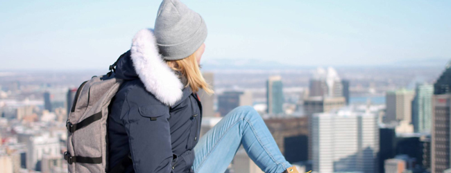 Eine Frau mit Jacke und Mütze blickt auf die Skyline von Montreal, Kanada