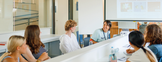 Unterricht an der LISA! Sprachschule in Malaga Mehrere Schüler nehmen am Unterricht teil und sprechen mit einer freundlichen Lehrerin in der Schule in Malaga