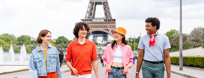Vier junge Leute stehen vor dem Eiffelturm bei einer LISA! Sprachreise Französisch in Paris